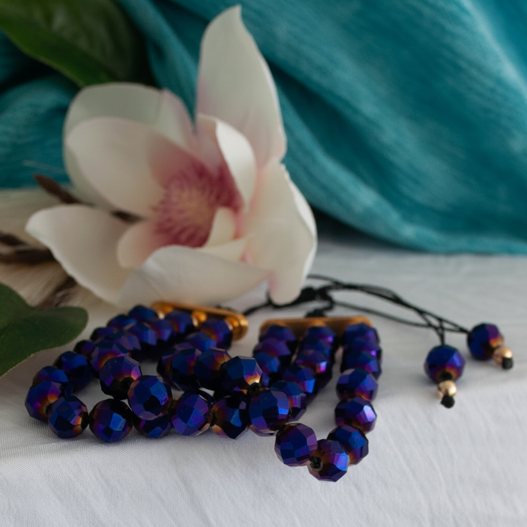 Cobalt blue vitrail glass bracelet styled on white fabric with a magnolia flower and teal backdrop.