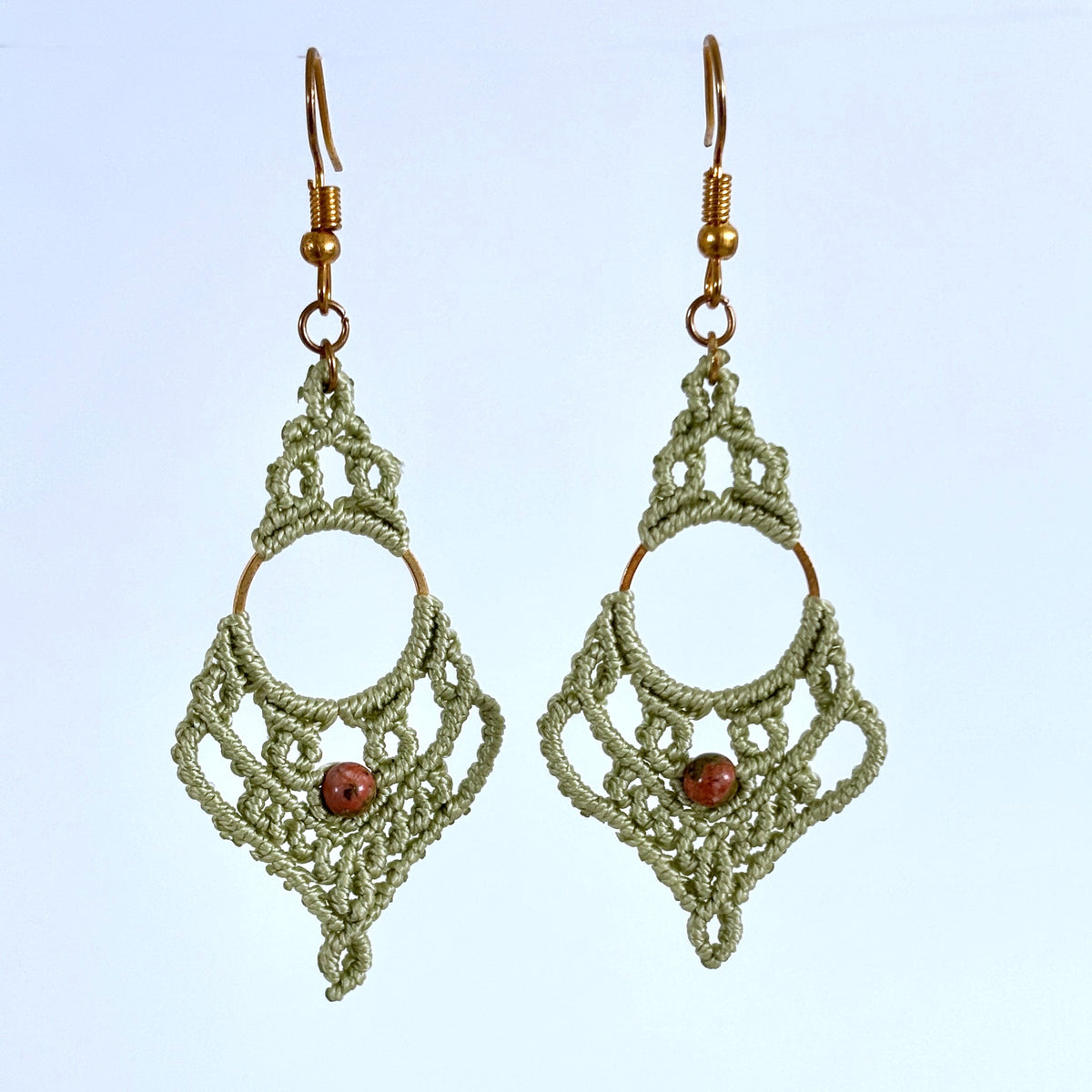 Handmade sage green lace macrame chandelier earrings with gold-tone ring and unakite bead, hanging against a neutral background