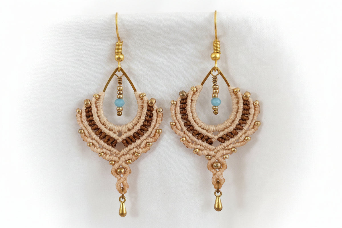 Pair of handmade two-tone sand and chocolate brown macrame crescent chandelier earrings with galvanized gold seed beads, turquoise crystal rondelle centers, and gold-tone waterdrop charms, displayed on white fabric background.