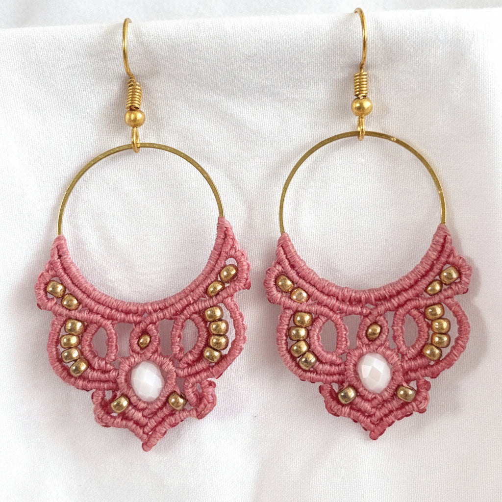 Salmon pink macrame hoop earrings with gold-tone hoops, gold seed beads, and white crystal rondelle centers.