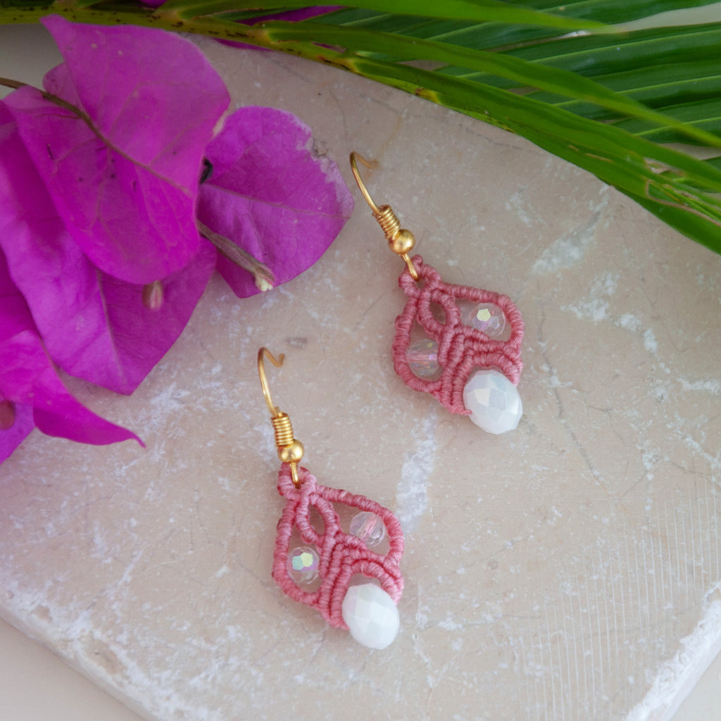 Salmon pink macrame lace drop earrings with iridescent crystal beads and white rondelles on travertine tile.