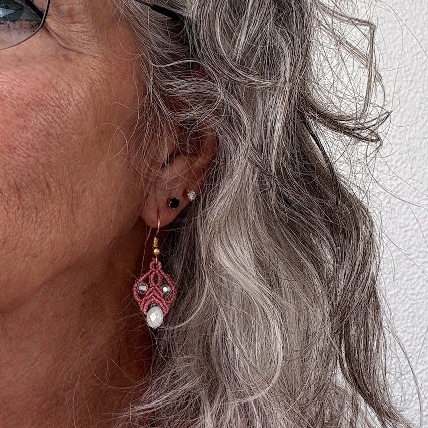 Salmon pink macrame lace drop earrings with iridescent crystals and white rondelle drops, shown worn.