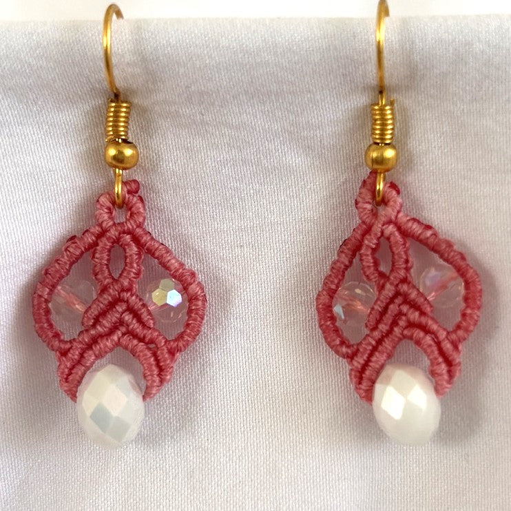 Salmon pink macrame lace drop earrings with iridescent crystal beads, a white rondelle, and gold-tone fishhook wires.