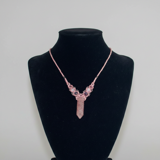 A pink crystal point pendant necklace displayed on a black velvet jewelry bust against a light gray background.