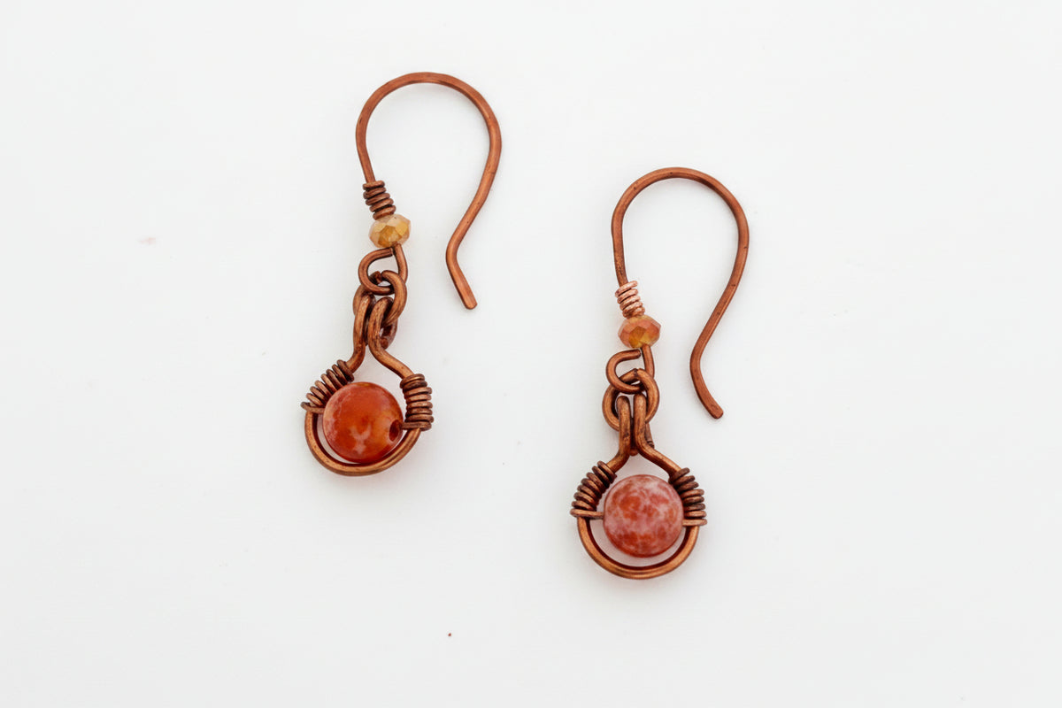 Handmade Ancient Cellar agate drop earrings with antiqued copper wire halo, 3mm iridescent orange crystal bead, and handcrafted hammered copper ear wires, flat lay on white background — one-of-a-kind boho gemstone earrings.