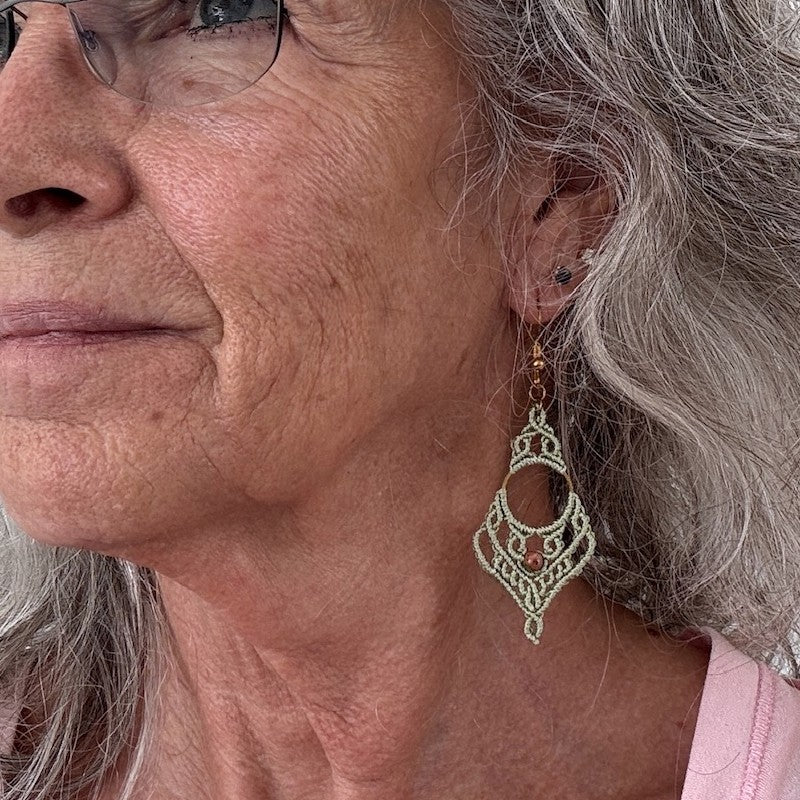 Sage green lace macrame chandelier earrings with unakite bead and gold-tone ear wire shown worn on model with silver hair
