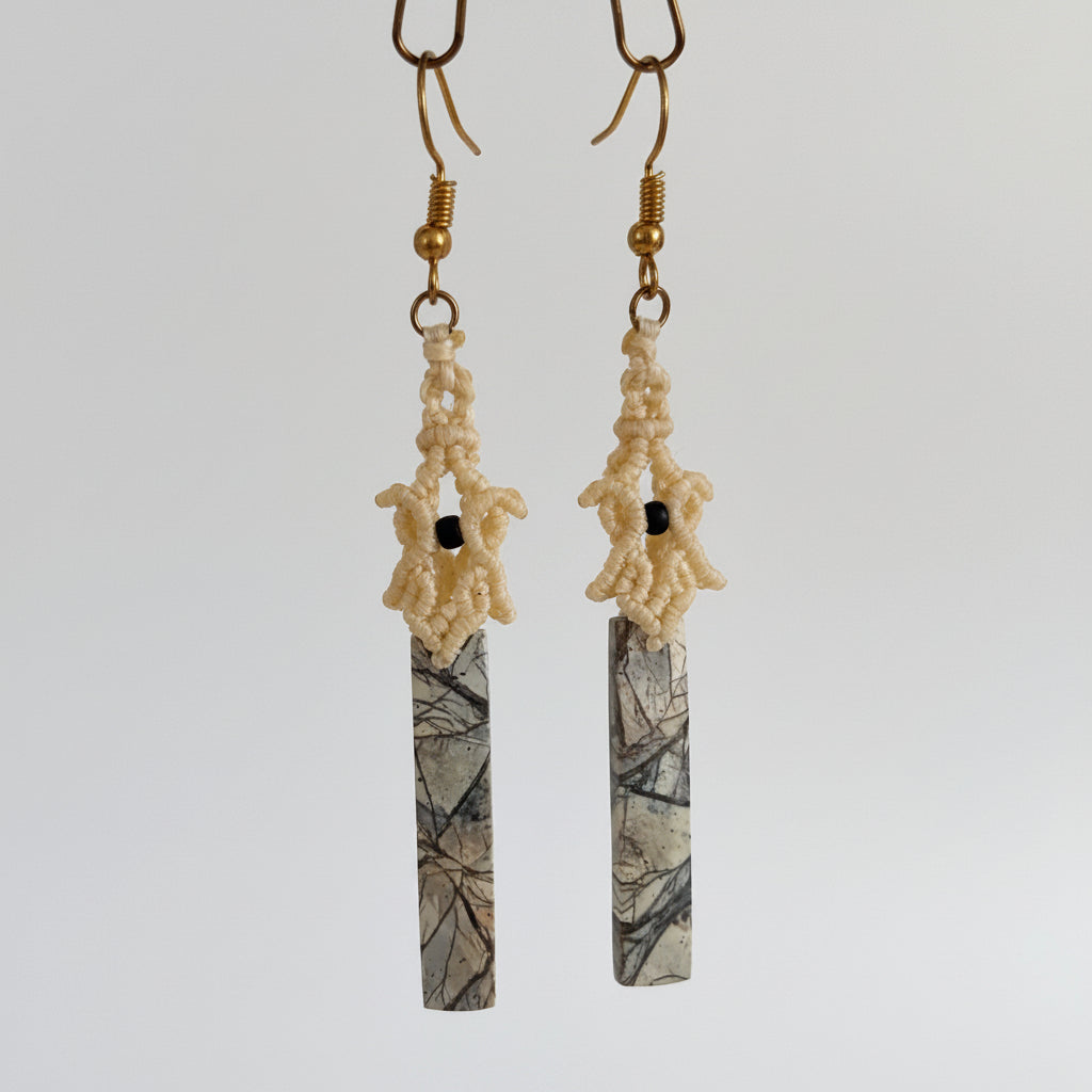 Handmade pale yellow lace macrame pagoda earrings with maligano jasper stick bead and matte black seed bead accents, hanging against a neutral background