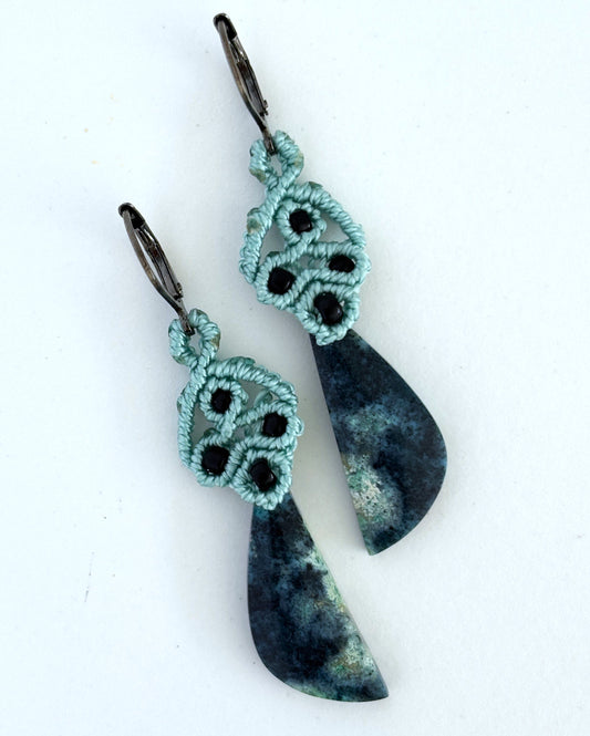 Teal macrame dangle earrings with black seed beads and dark teal and charcoal Bacan stone pendants on a white background