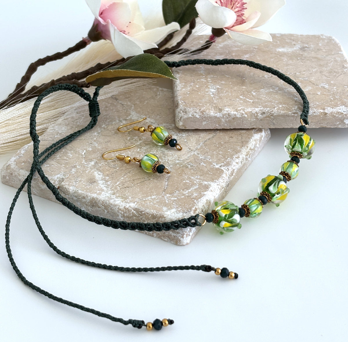 Clear swirl lampwork glass necklace styled with coordinating yellow, green, and white lampwork earrings.