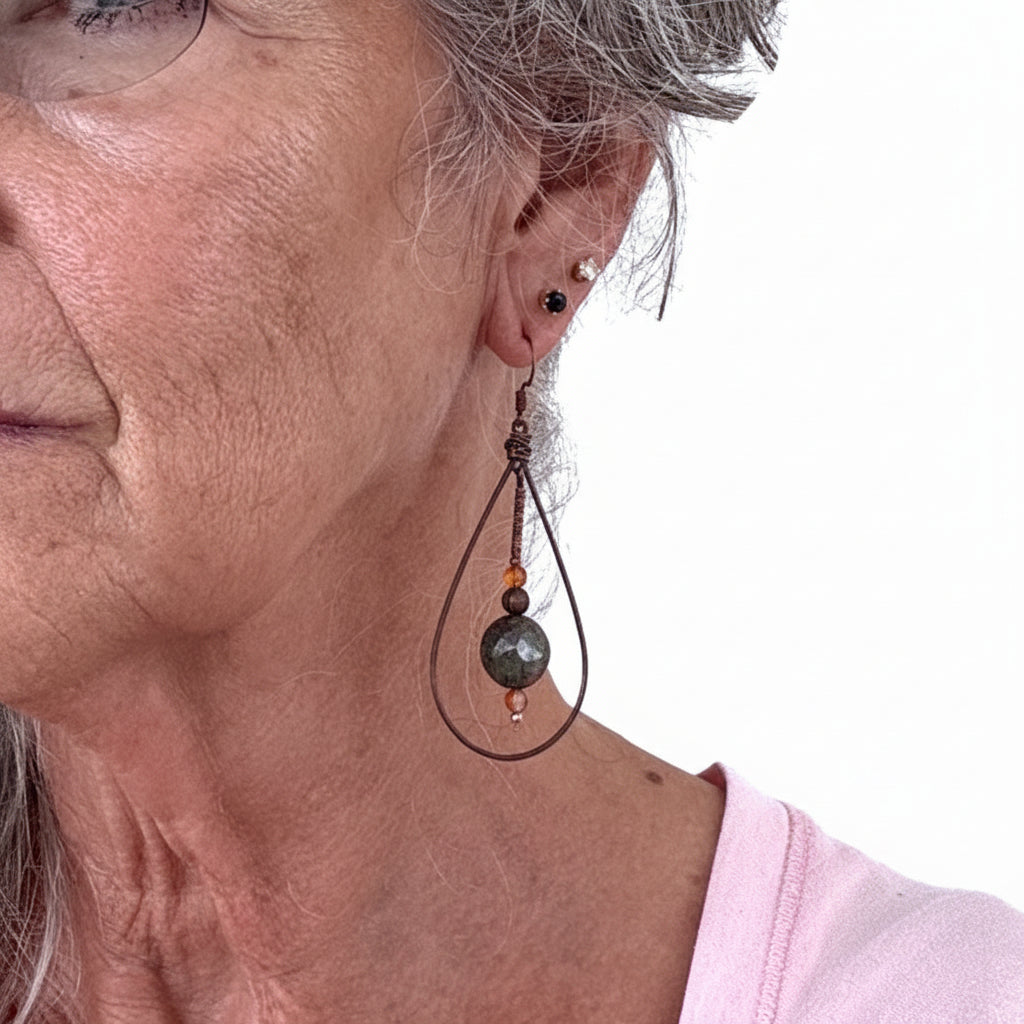Copper teardrop earring with unakite disc and carnelian bead drop shown worn on model with silver hair