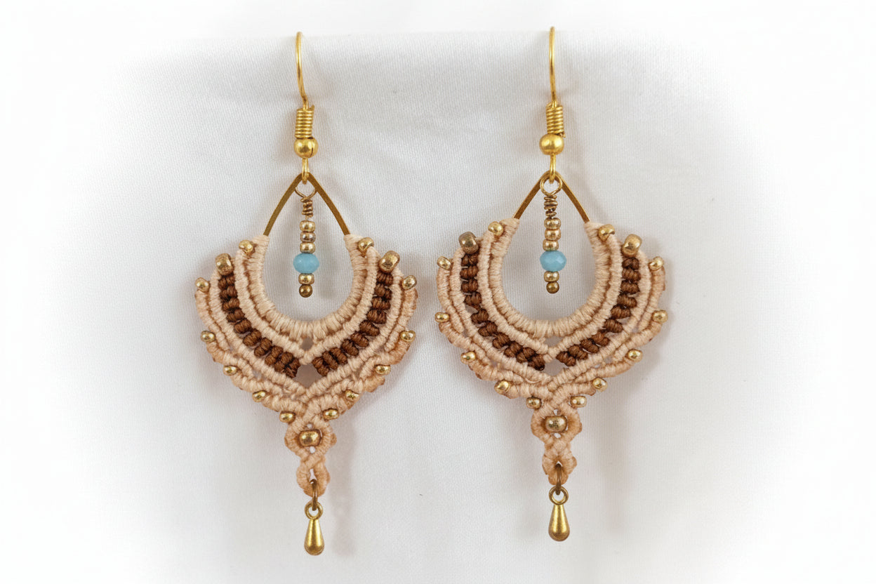 Pair of handmade two-tone sand and chocolate brown macrame crescent chandelier earrings with galvanized gold seed beads, turquoise crystal rondelle centers, and gold-tone waterdrop charms, displayed on white fabric background.