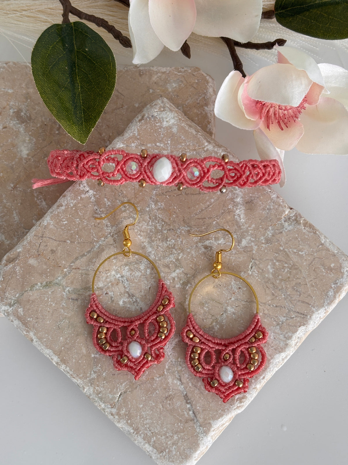 Salmon pink macrame bracelet displayed with coordinating salmon pink hoop drop earrings, each sold separately.