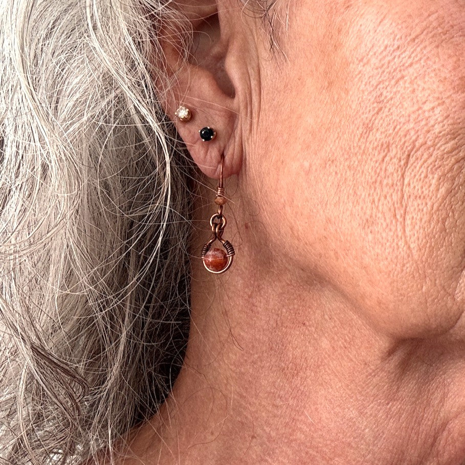 Handmade Ancient Cellar agate drop earring with antiqued copper wire halo worn in ear, showing scale and wearability — one-of-a-kind artisan boho gemstone earring by MJ Skivers Designs.