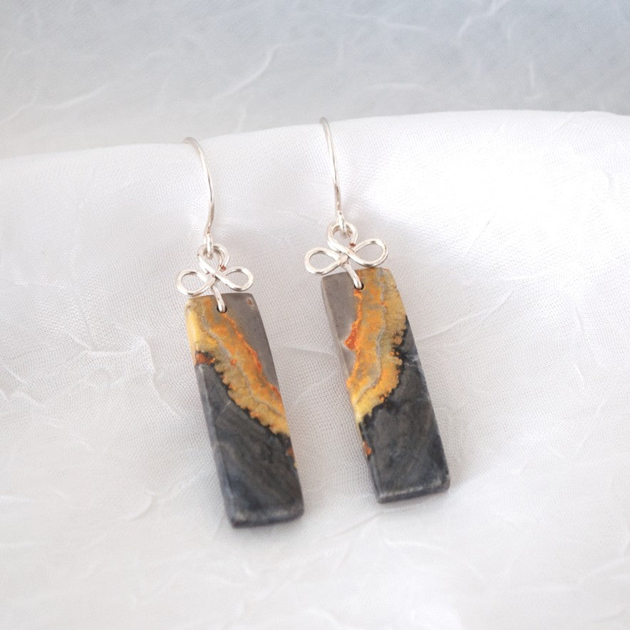 Handmade bumble bee jasper earrings with silver-tone handcrafted bail and ear wires, displayed on white linen surface showing charcoal and amber stone detail
