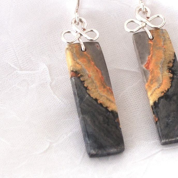 Close-up detail of bumble bee jasper earrings showing charcoal, amber, and rust stone patterning with silver-tone handcrafted bail
