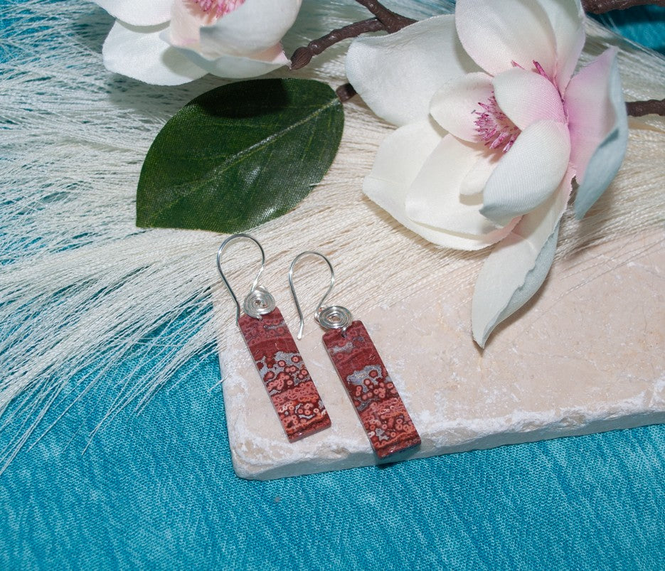 Brecciated jasper earrings with silver-tone handcrafted swirl bail displayed on travertine tile with magnolia flower and teal linen background