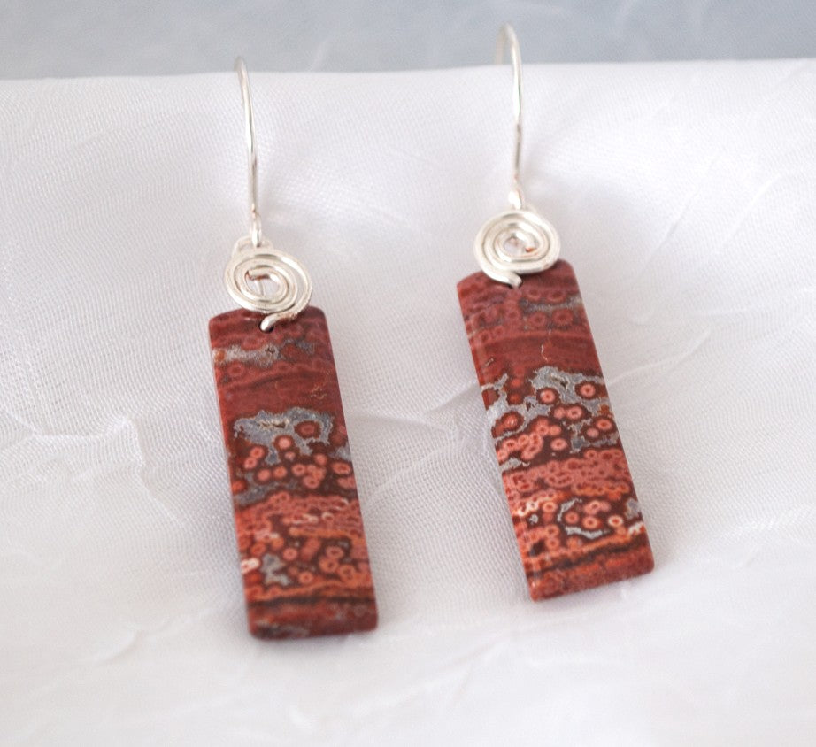 Brecciated jasper earrings with silver-tone swirl bail and hammered ear wires displayed on white linen surface