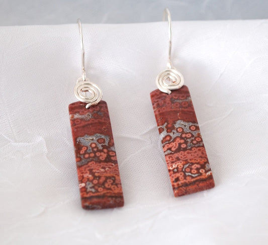 Brecciated jasper earrings with silver-tone swirl bail and hammered ear wires displayed on white linen surface