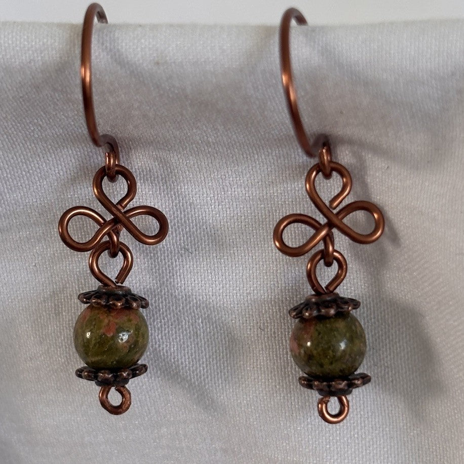 Close-up of handmade unakite gemstone drop earrings showing antique copper clover charm, copper bead caps, and 6mm unakite bead detail.