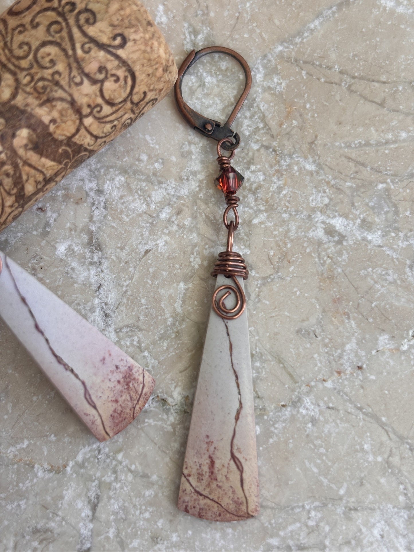 Close-up of handmade porcelain jasper drop earring showing antique copper leverback, Swarovski bicone crystal charm, spiral wire wrap detail, and natural stone veining.