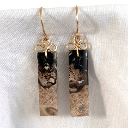 Handmade petrified palm earrings with brass handcrafted clover bail and ear wires showing black to cream stone gradient, displayed on white linen background