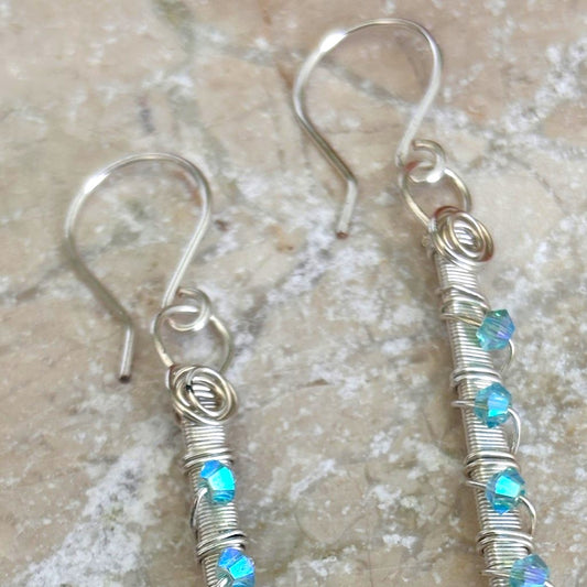 Close-up of aqua Swarovski crystal earring showing hand-coiled silver-plate wire ring, tightly coiled wire-wrapped bar, and 3mm aqua Swarovski bicone crystal accents