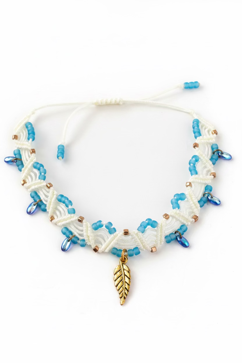 A handmade ivory macrame anklet with turquoise matte seed beads, gold Miyuki square seed beads, iridescent blue Czech glass water drop beads, and a gold-tone leaf charm, displayed on a white background showing the full piece and adjustable slide closure.
