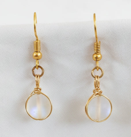Pair of handmade frosted mermaid glass drop earrings with brass wire wrapping and gold-tone fish hook wires, displayed on white background.