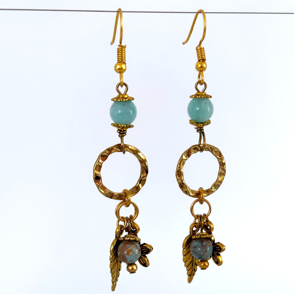 Handmade gold-tone textured ring earrings with amazonite bead, blue calsilica drop, and gold-tone leaf and flower charms, hanging against a white background